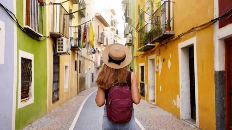 Pakistani digital nomad walking in a colorful Spanish street with backpack showing realistic accommodation planning for Spain nomad visa
