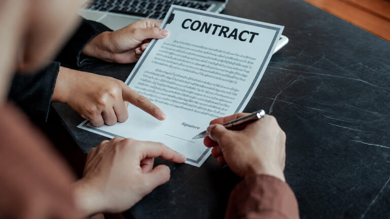 Hands signing a detailed Freelancer Contract for Slovenia Nomad Pass.
